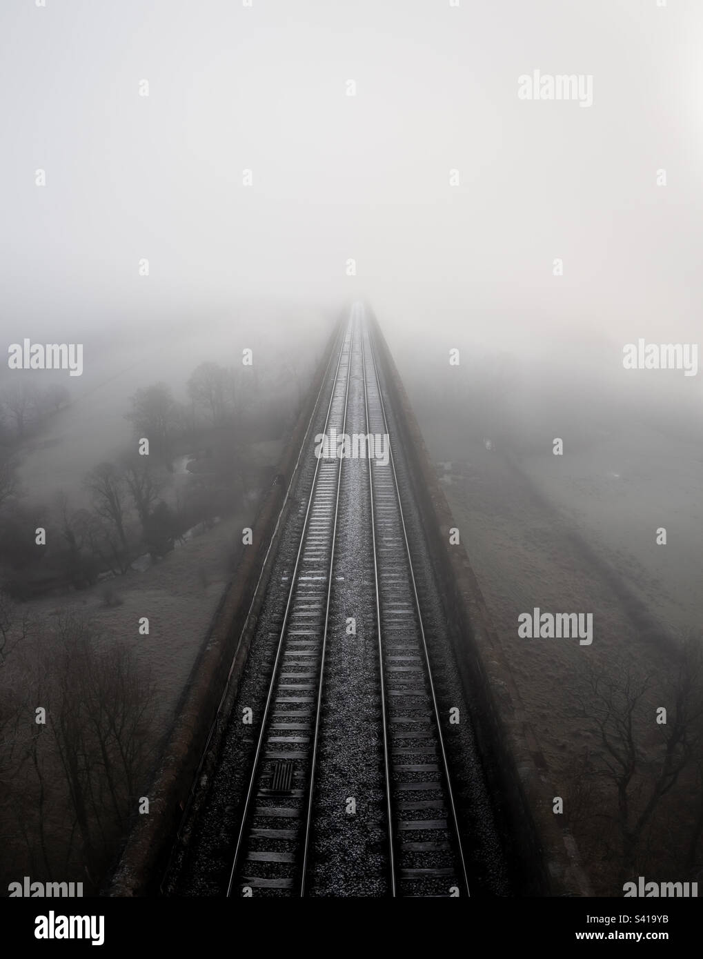 Railway tracks disappearing into the distance on a cold foggy morning during Winter months - Smartphone Captured Stock Image