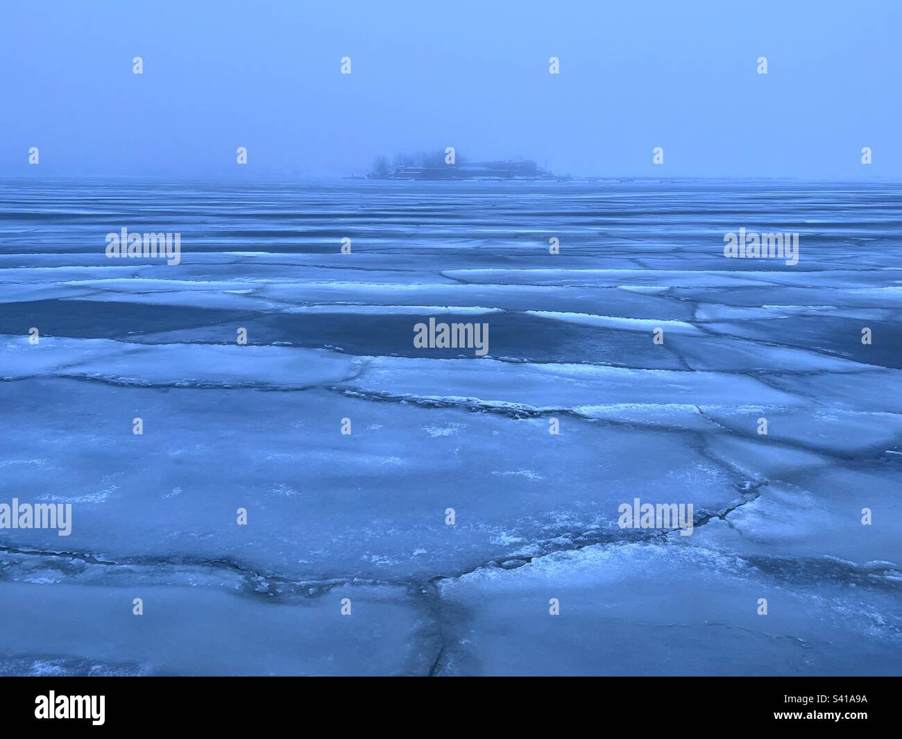Blue moment tranquil scene with icefloes on the sea surface and far island in foggy air - Smartphone Captured Stock Image