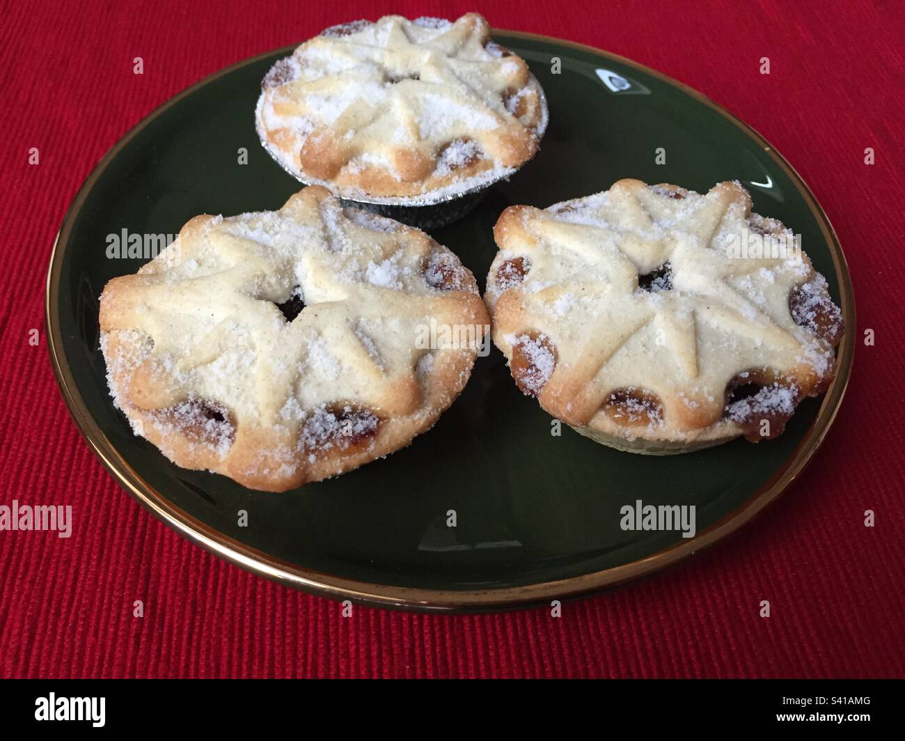 Mince pies on a dark green plate with a gold rim, traditional Christmas treats, pic 7. - Smartphone Captured Stock Image