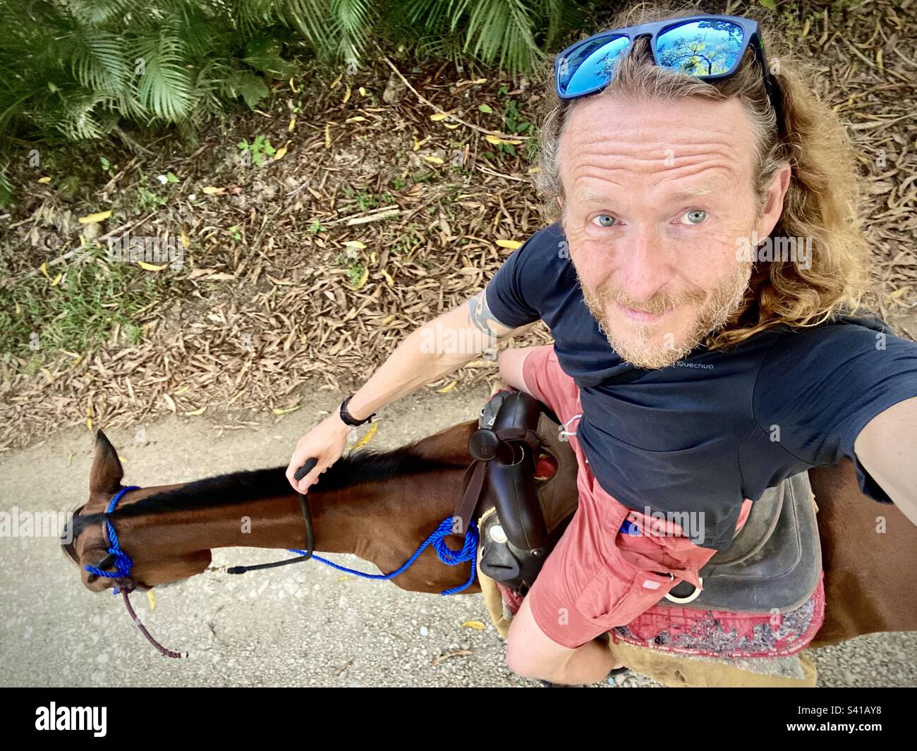 A man takes a selfie while on a horseback ride in the forest in Costa Rica - Smartphone Captured Stock Image