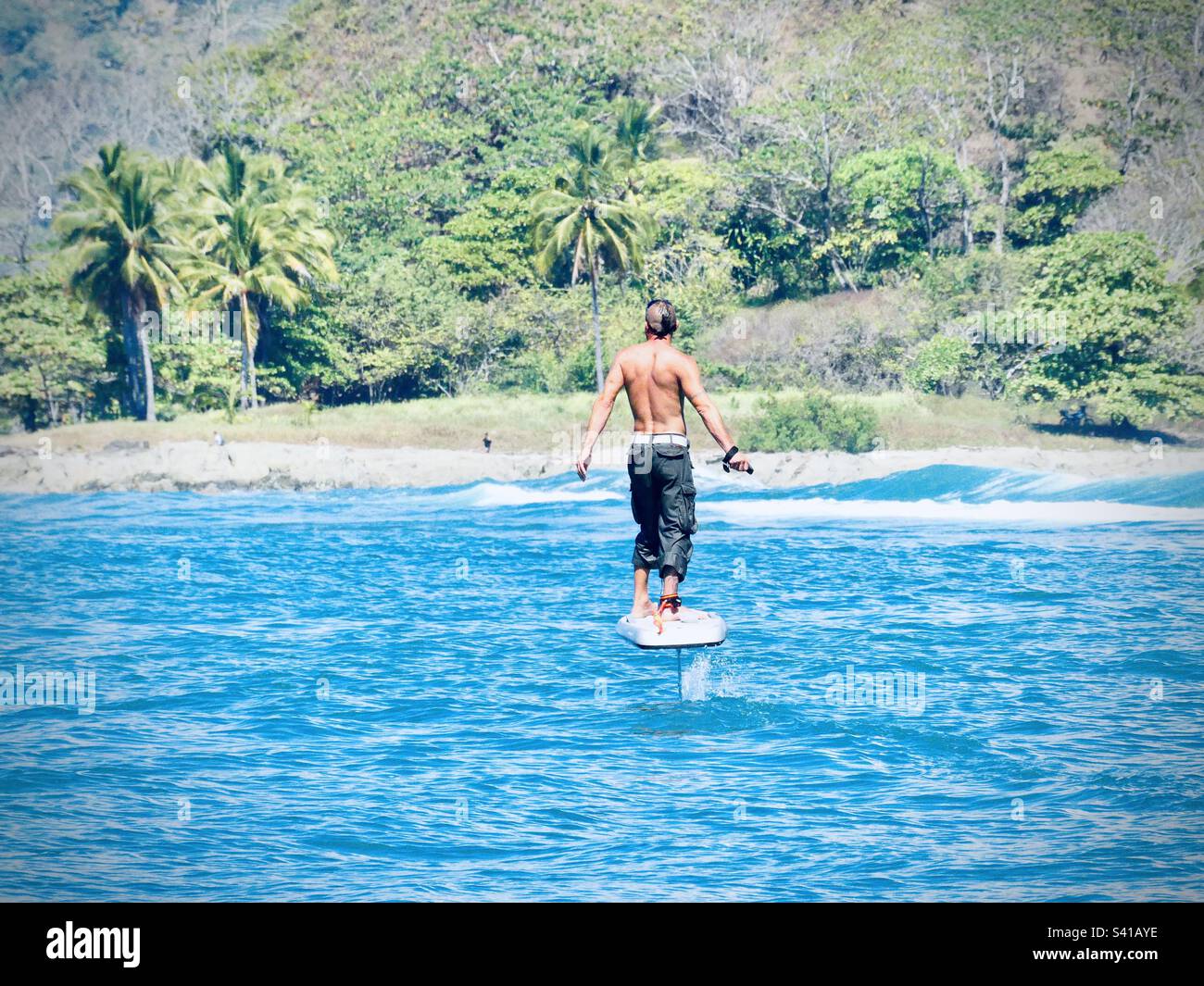 A man rides a foil board on the water near Santa Teressa in Costa Rica - Smartphone Captured Stock Image