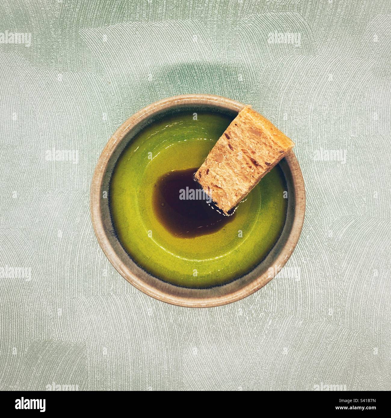 Olive oil and balsamic vinegar dip in a green bowl with a finger of wholemeal bread - Smartphone Captured Stock Image