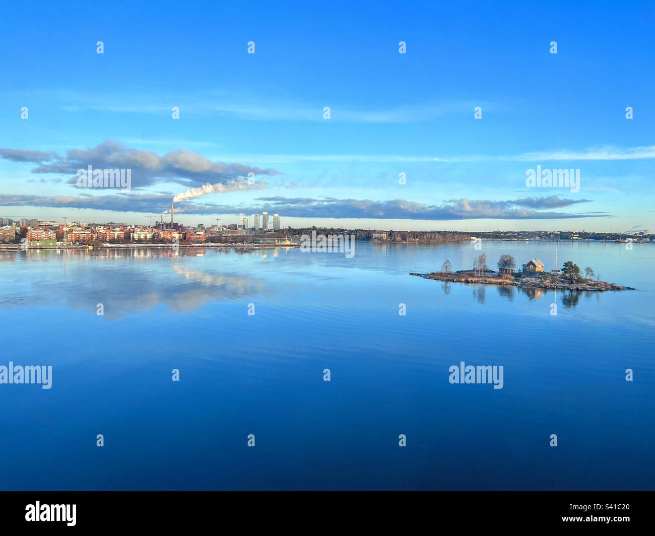 Tranquil scene horizon over Baltic Sea with cityscape, smoking pipe and little island with trees and small cottage - Smartphone Captured Stock Image