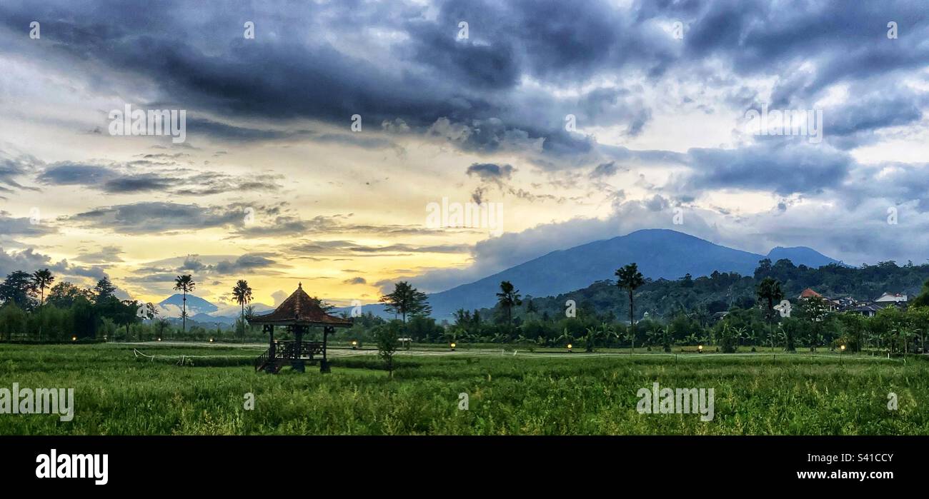 Panoramic view over rice fields of Mt Ungaran and Mt Merapi Volcanos in Central Java Indonesia at Sunset Stock Photo