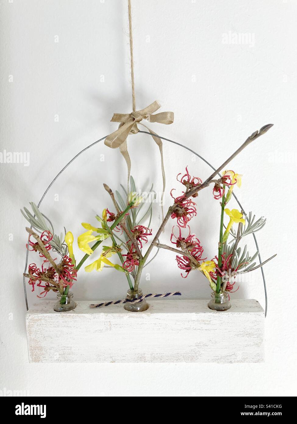 Winter blossoms in three small vases hanging on a wall Stock Photo