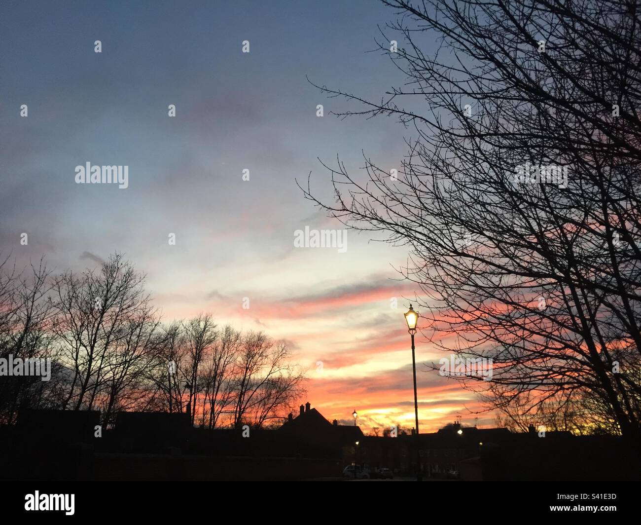 Sunset, Colourful sky with silhouetted trees, rooftops and lamp posts. UK, January 2023 pic 6. - Smartphone Captured Stock Image