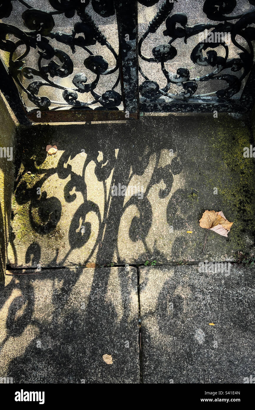 Ornamental iron gate scrollwork casting shadow on walkway - Smartphone Captured Stock Image Ornamental iron gate scrollwork casting shadow on walkway - Smartphone Captured Stock Image