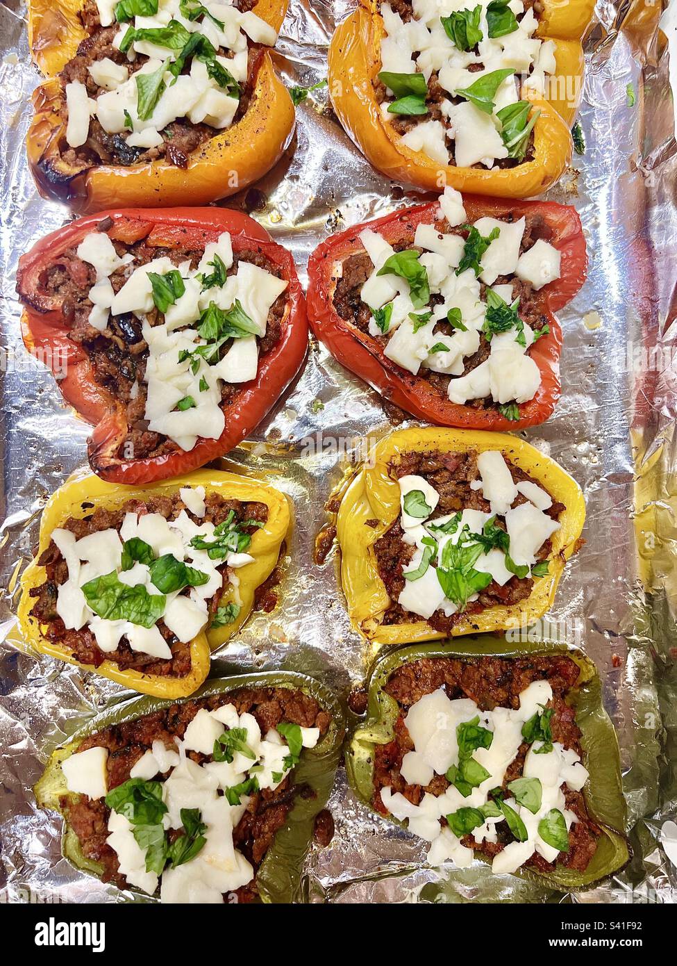 Stuffed bell peppers (Capsicum annuum) with ground minced beef cheese and herbs ready for roasting Stock Photo