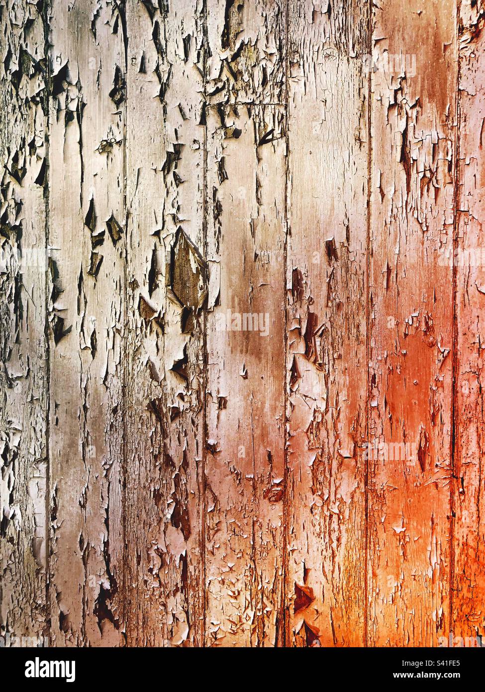 Full frame background of a wooden surface with peeling paint and a glow from the heat of a fire - Smartphone Captured Stock Image