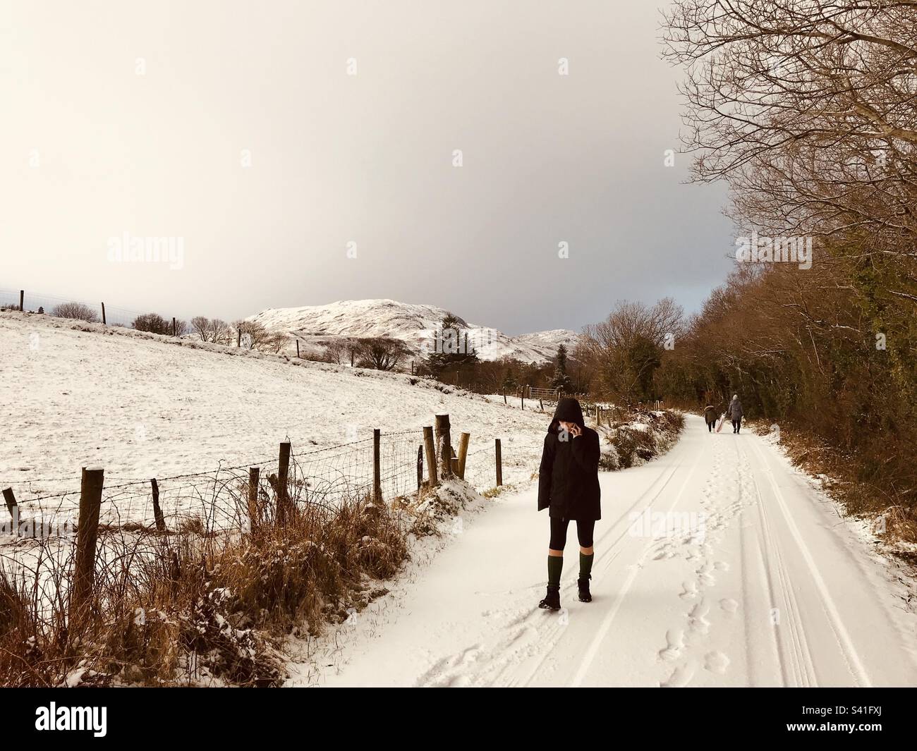 Young woman walking in snow, County Donegal, Ireland - Smartphone Captured Stock Image