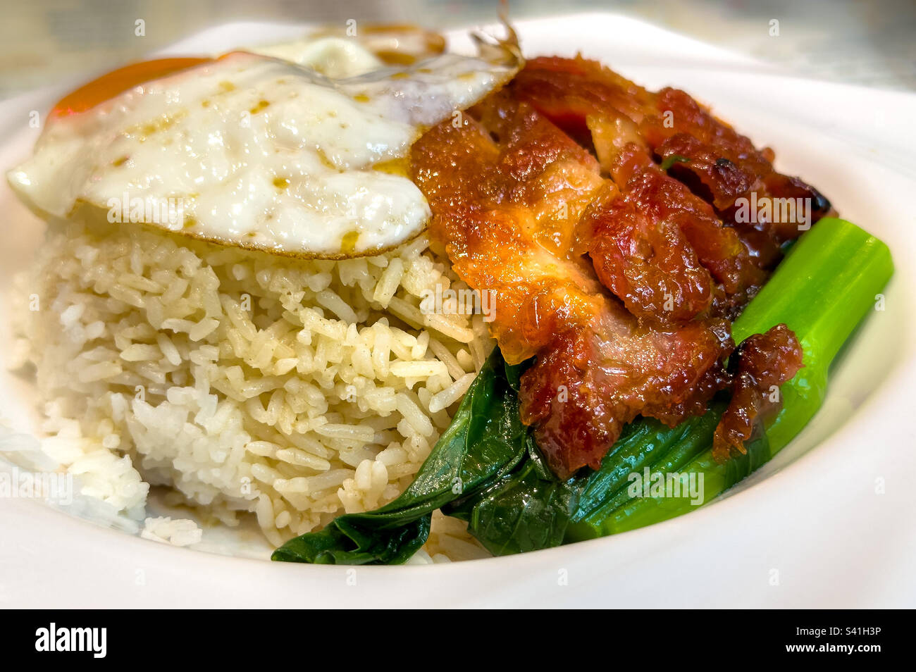Closeup of bowl of Chinese barbecue pork (char Sui) rice with fried egg and vegetables Stock Photo