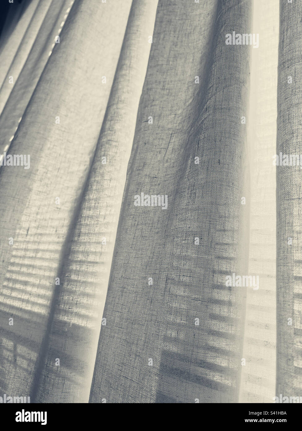 White cotton curtains drifting in the breeze from an open window. - Smartphone Captured Stock Image