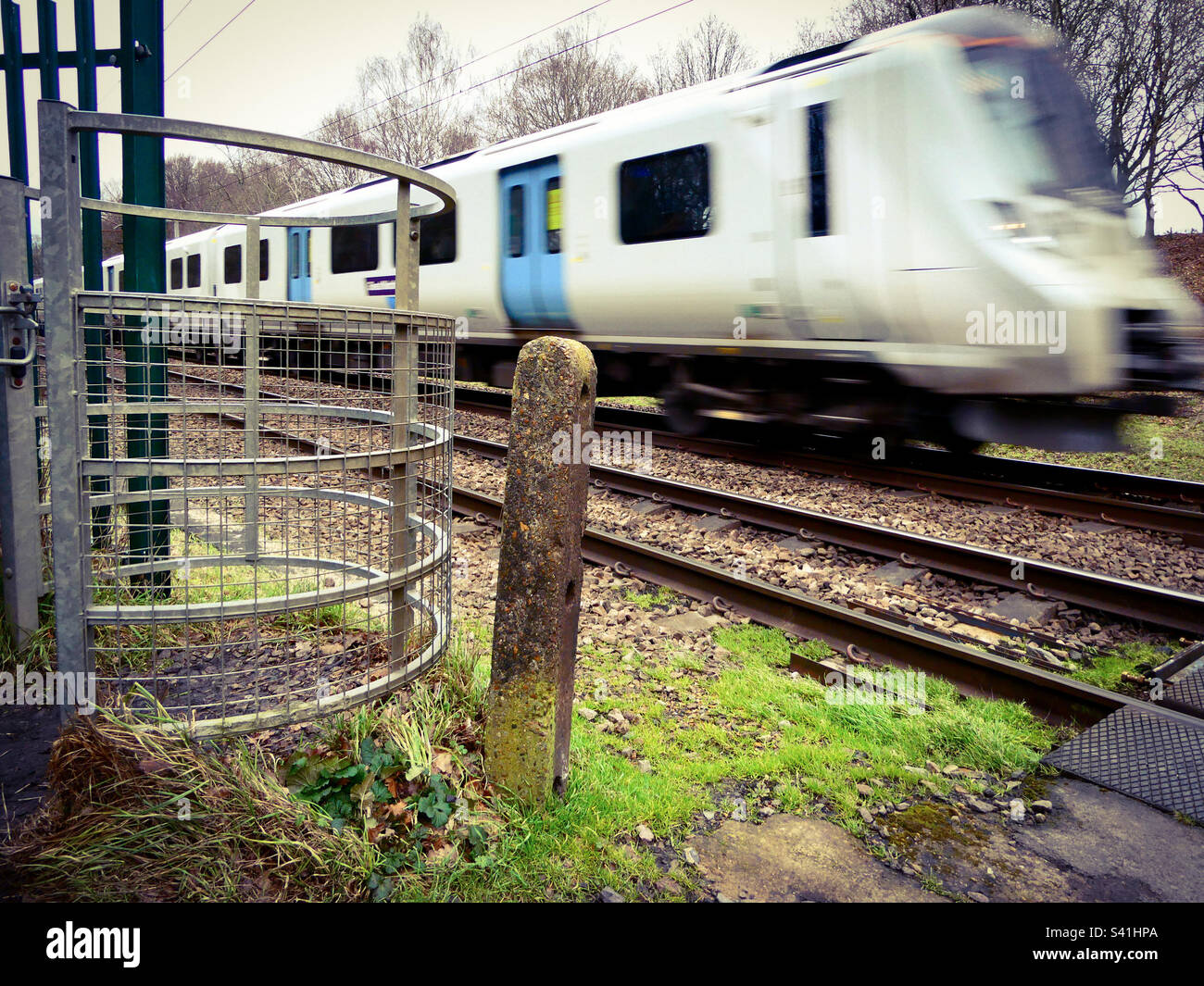 A fast train passes close by near a crossing place in North London in England - Smartphone Captured Stock Image
