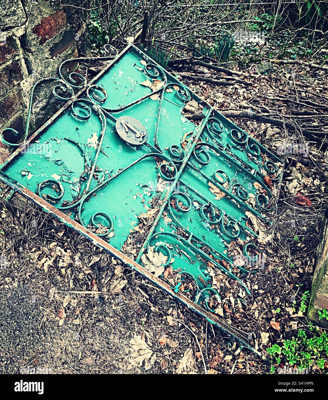 Old metal gate lying on its side on roadside in between low stone walls