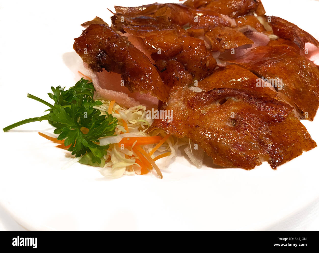 Plate of crispy Peking Duck on bed of vegetables and shrimp chips, a traditional culinary delicacy in Chinese cuisine Stock Photo