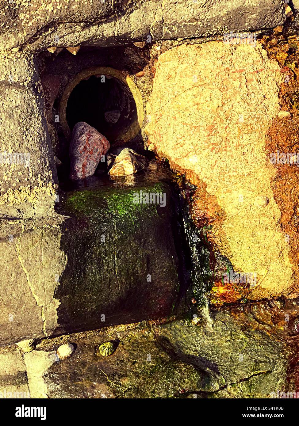 Running water outlet from the road to the beach in Torquay Devon changing the rock colouring