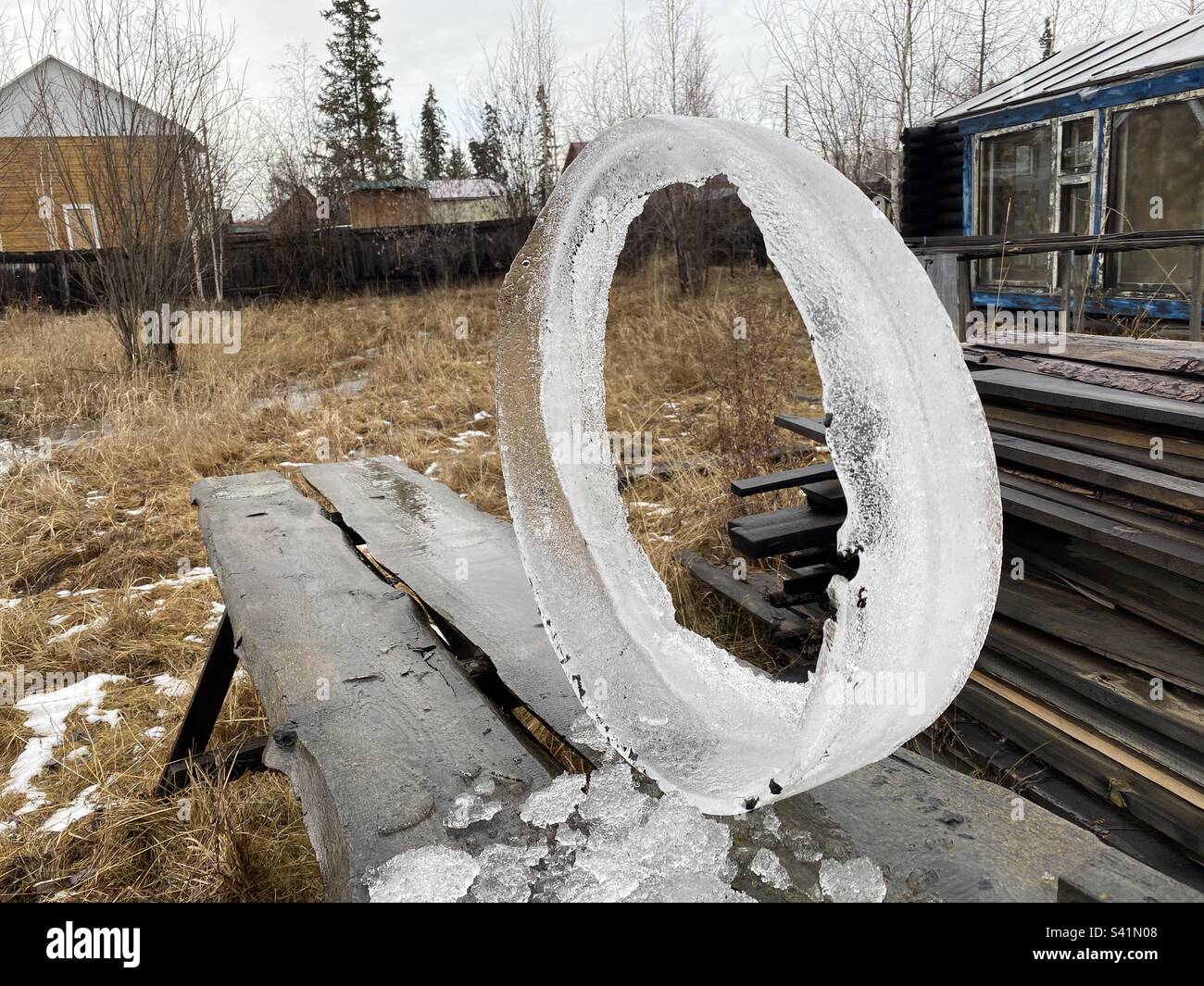 A round piece of ice with a hole inside in the form of the digit zero, lies on a village plot in Yakutia. - Smartphone Captured Stock Image