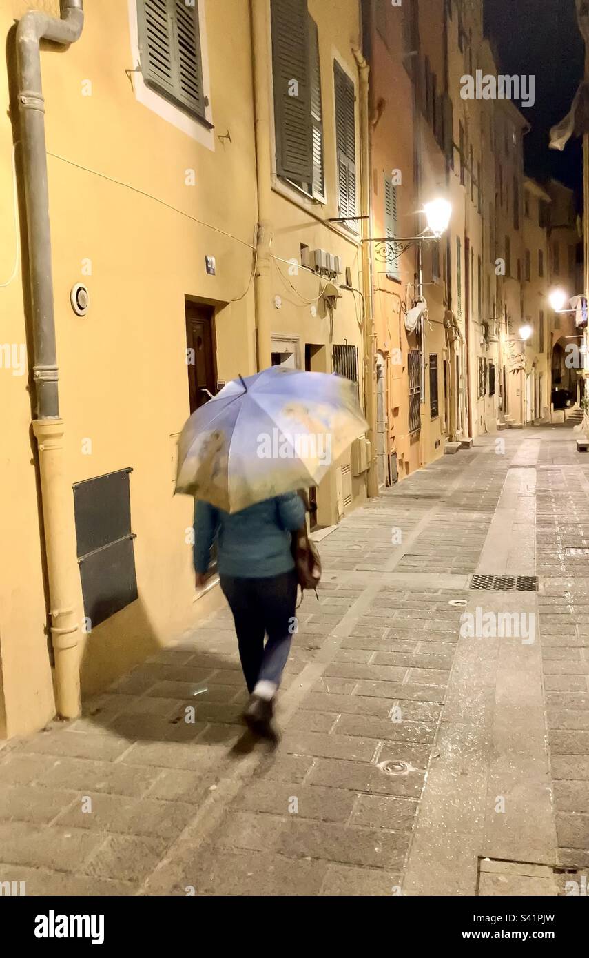 Woman walking in the old town of Menton, France on a rainy Spring evening. - Smartphone Captured Stock Image