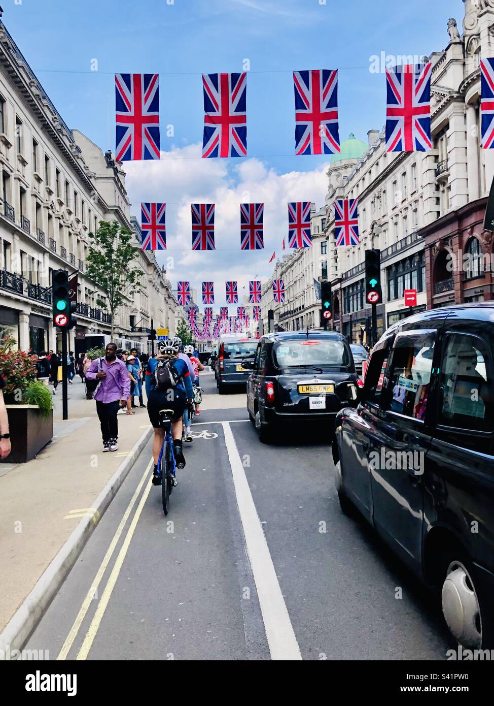 A view of a major street in London with Taxi cabs and Union Jack flags - Smartphone Captured Stock Image