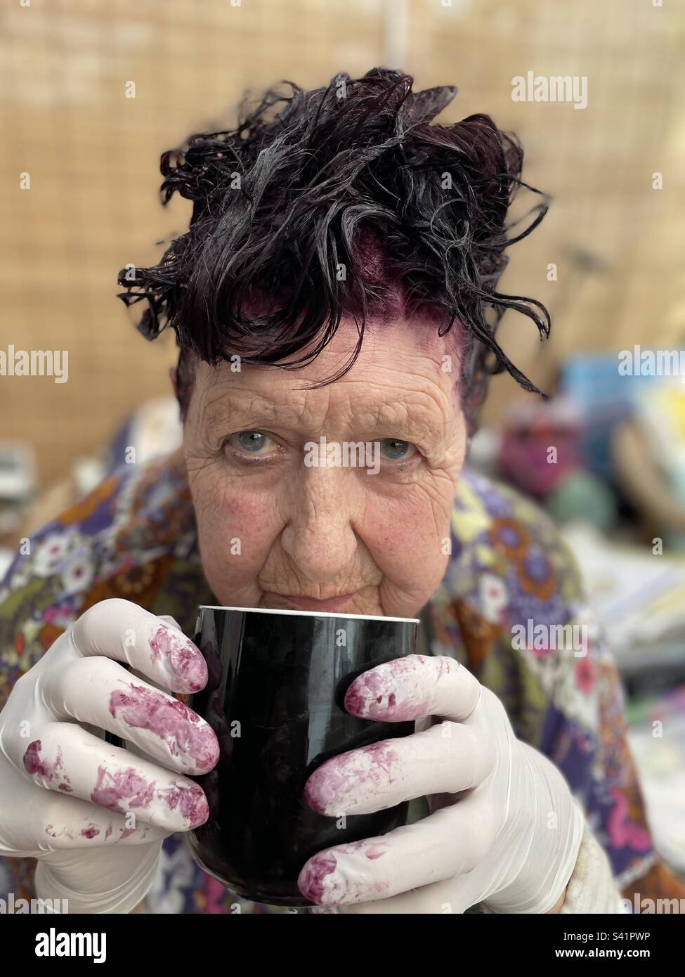 Woman drinking a coffee while waiting for her hair dye to set - Smartphone Captured Stock Image