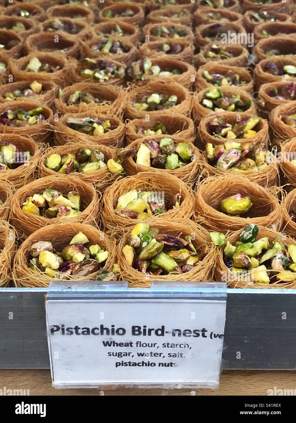 Pistachio nut bird nest, a Syrian and Middle Eastern sweet treat in bakery window - Smartphone Captured Stock Image