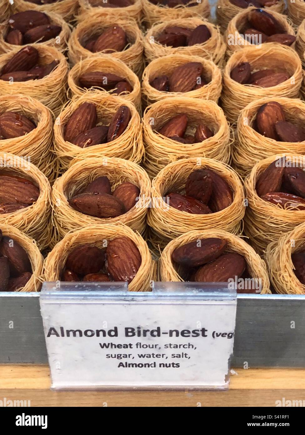 Almond nut bird nest, a Syrian and Middle Eastern sweet treat in bakery window - Smartphone Captured Stock Image