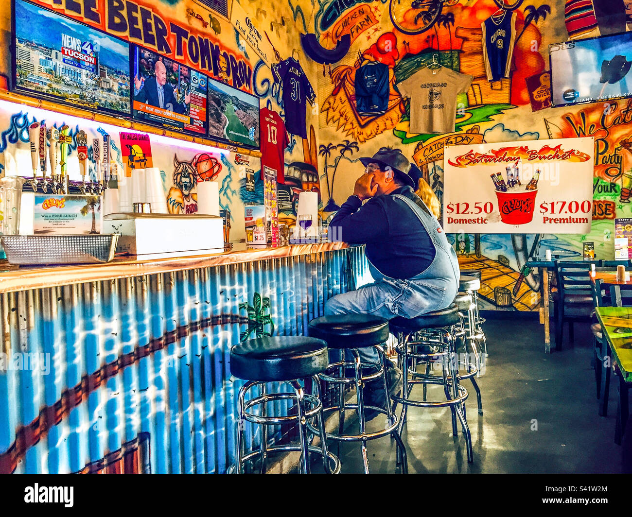 A man in dungarees sits on a bar stool at a bar in Nevada - Smartphone Captured Stock Image