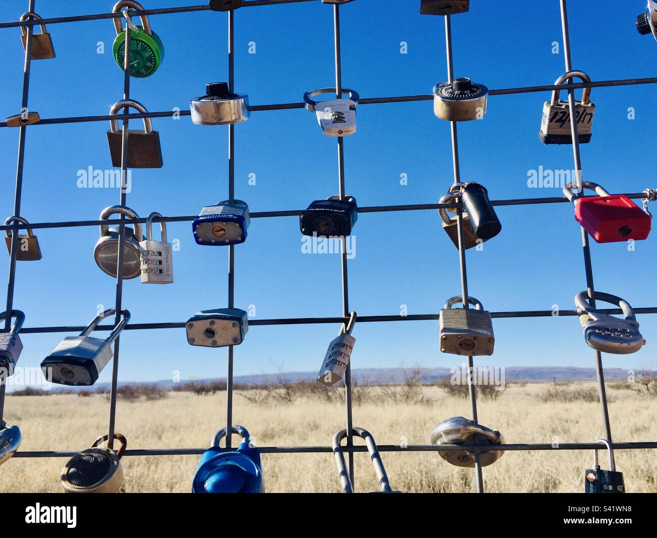 Locked Padlocks on a fence against a very nlue sky in the desert in West Texas - Smartphone Captured Stock Image