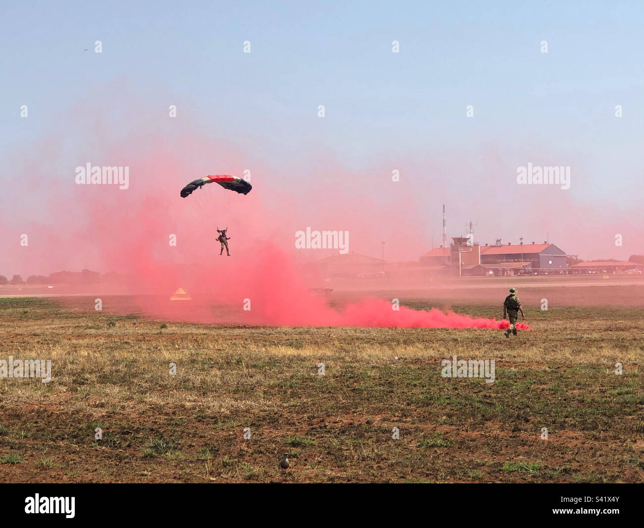 Parachutist at an air show coming in to land with red smoke on the drop zone - Smartphone Captured Stock Image