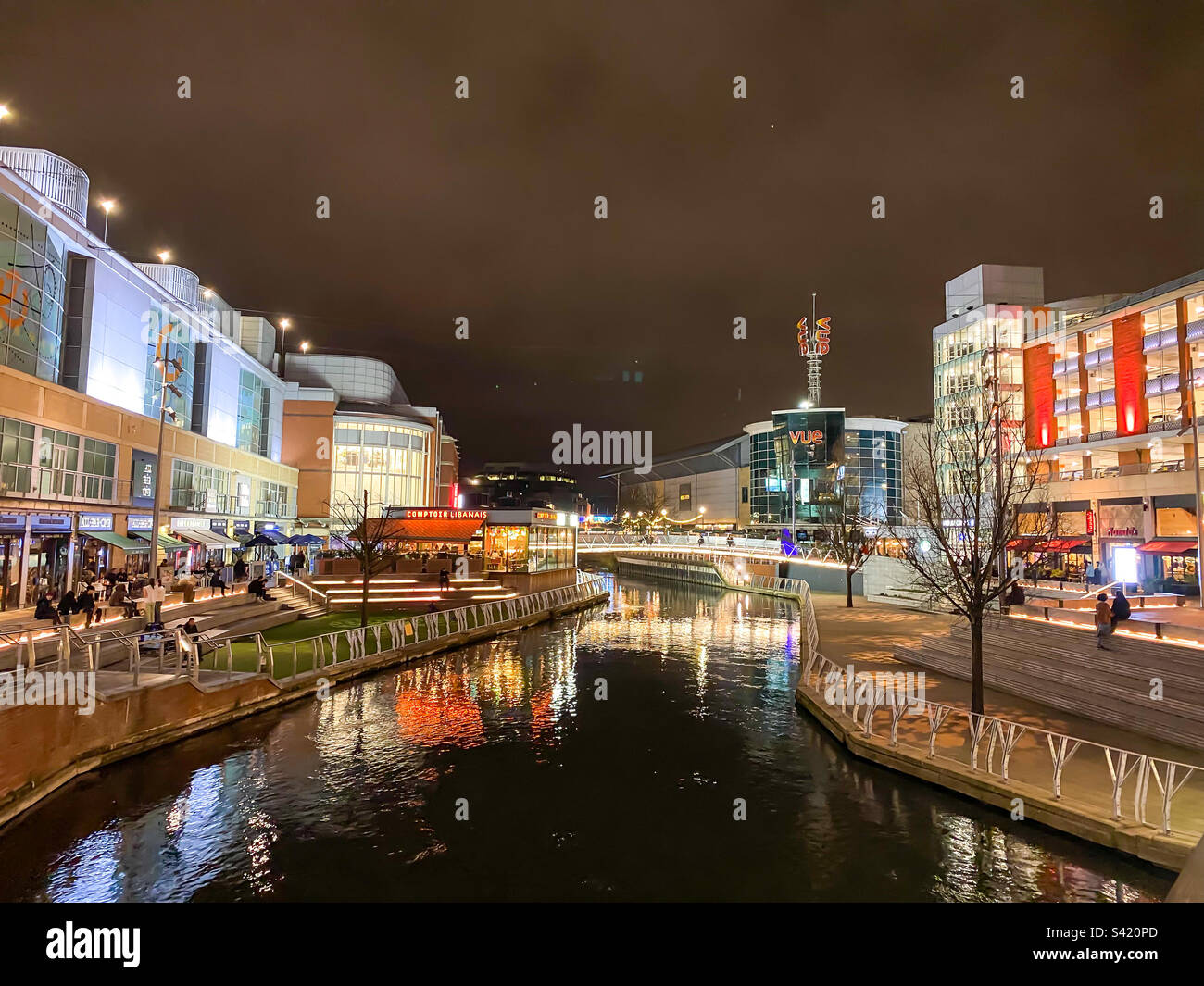 A view of shops and restaurants with bright lights at The Riverside part of The Oracle Centre in Reading, UK at night Stock Photo