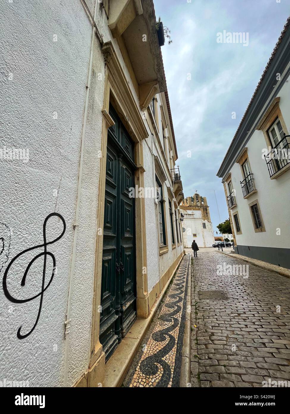 Treble clef graffiti on a wall - Main Street leads to the Cathedral in Faro City the historic centre with cobblestones and tiles in Portuguese style - Smartphone Captured Stock Image