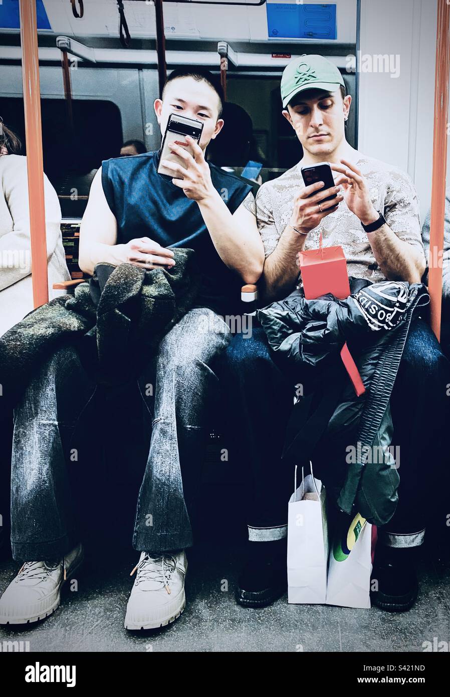 Two men looking at their phones on the underground in London UK - Smartphone Captured Stock Image