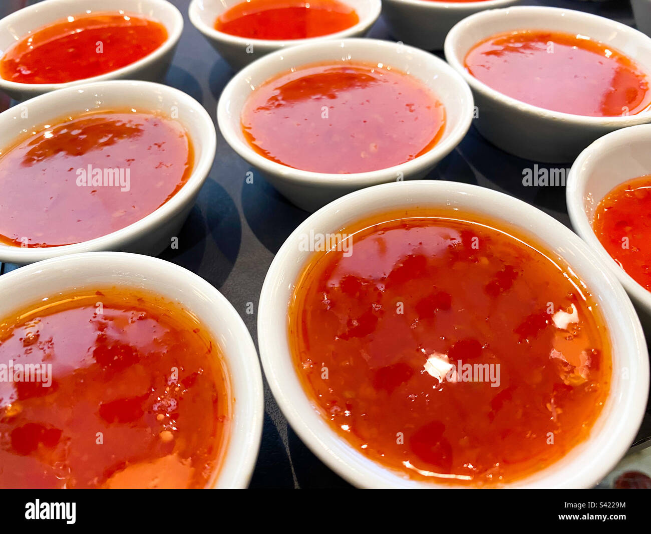 Small, white dishes of sweet chilli sauce. - Smartphone Captured Stock Image