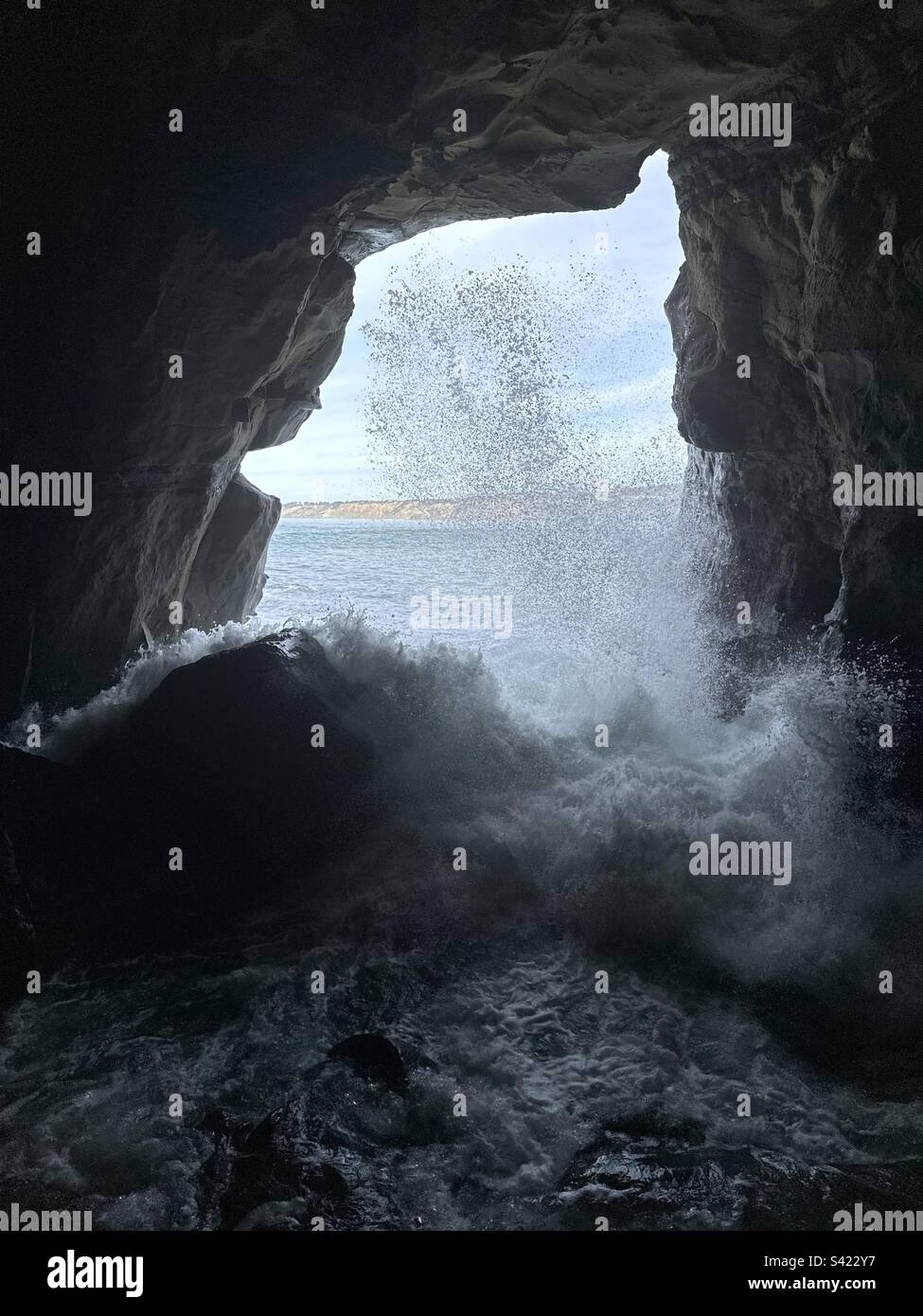 VlLoojing out from inside the Sunny Jim Cave in La Jolla, California, as a wave breaks on the rocks. Stock Photo