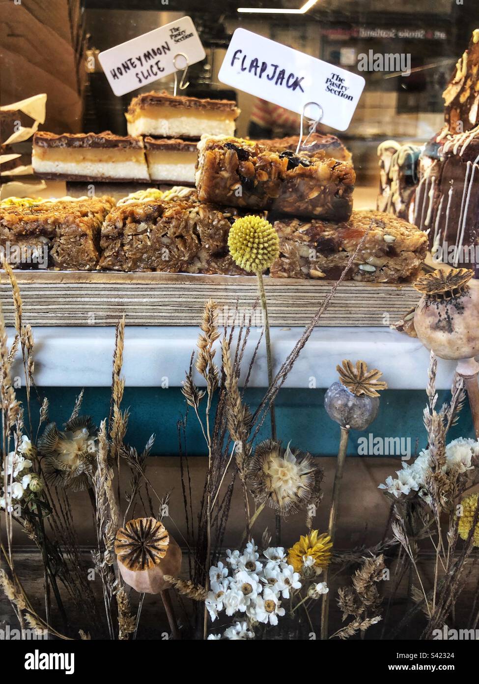 Flapjacks and Honeymoon Slice for sale in bakery window - Smartphone Captured Stock Image
