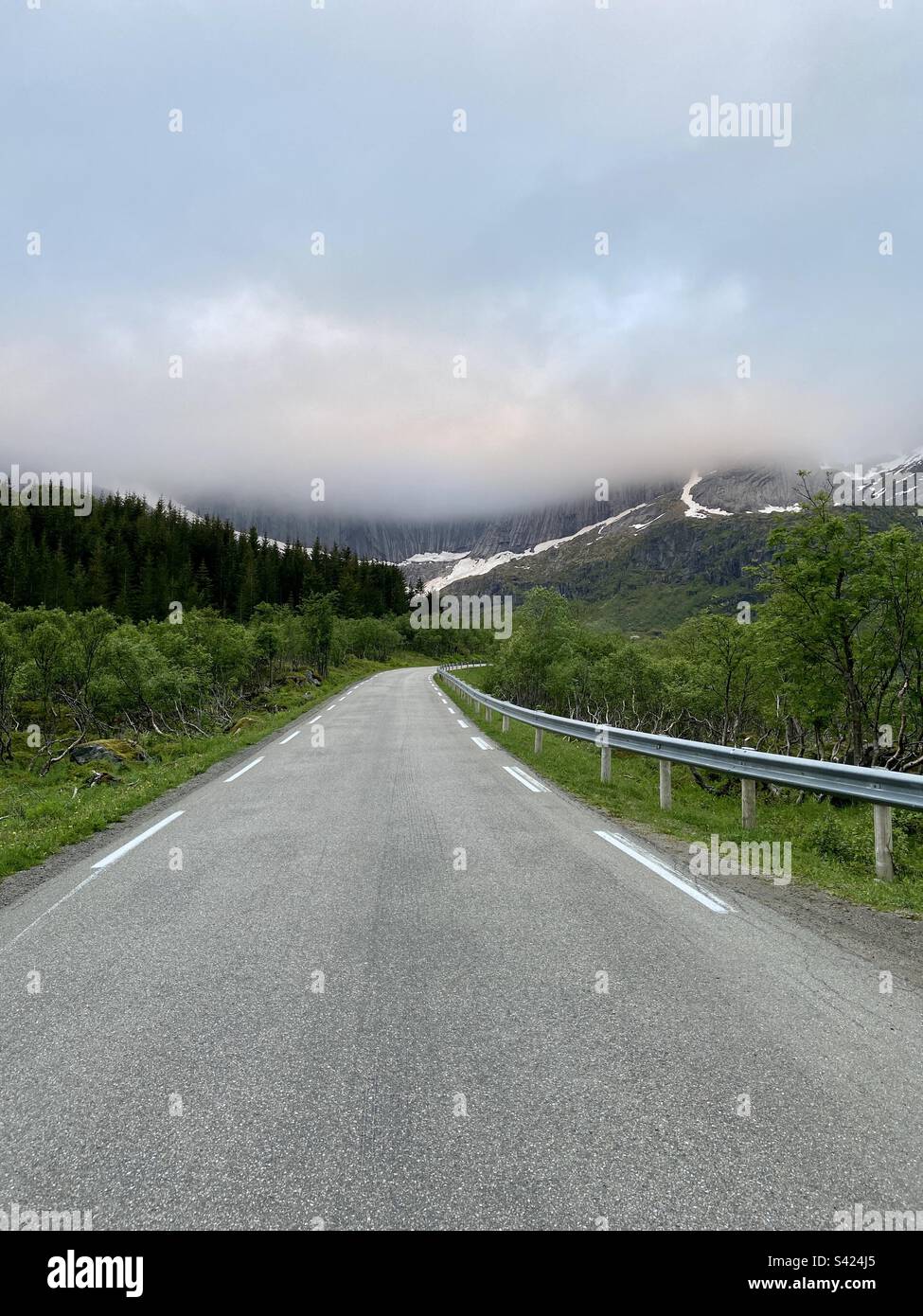 On the way to the Nusfjord in Lofoten islands, Norway. Mountain tops in the clouds. Photo of an asphalt road. - Smartphone Captured Stock Image
