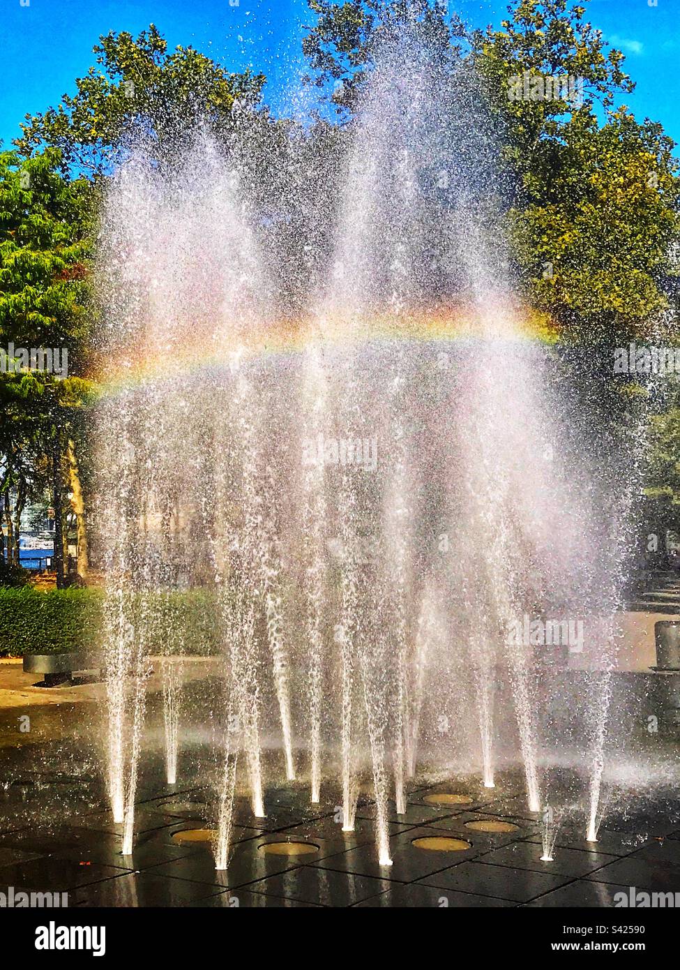 Rainbow through a fountain in a park. Stock Photo