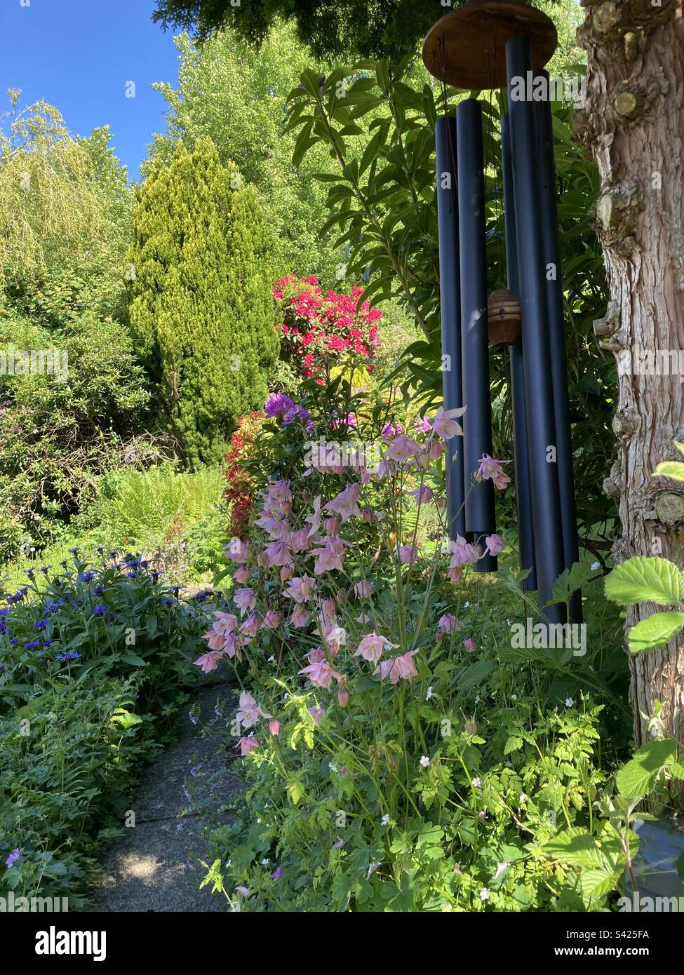 Large wind chime with flowering shrubs Stock Photo