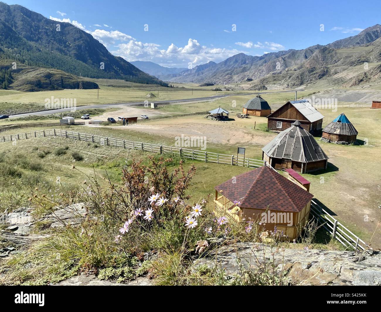 Altai national cottages ails stand in a field near the mountains against the background of flowers in Siberia. - Smartphone Captured Stock Image