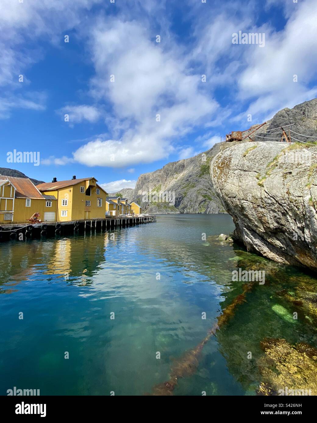 Fishing village Nusfjord in Norway, Lofoten islands on a sunny summer day. Yellow houses of a port also in the photo. - Smartphone Captured Stock Image