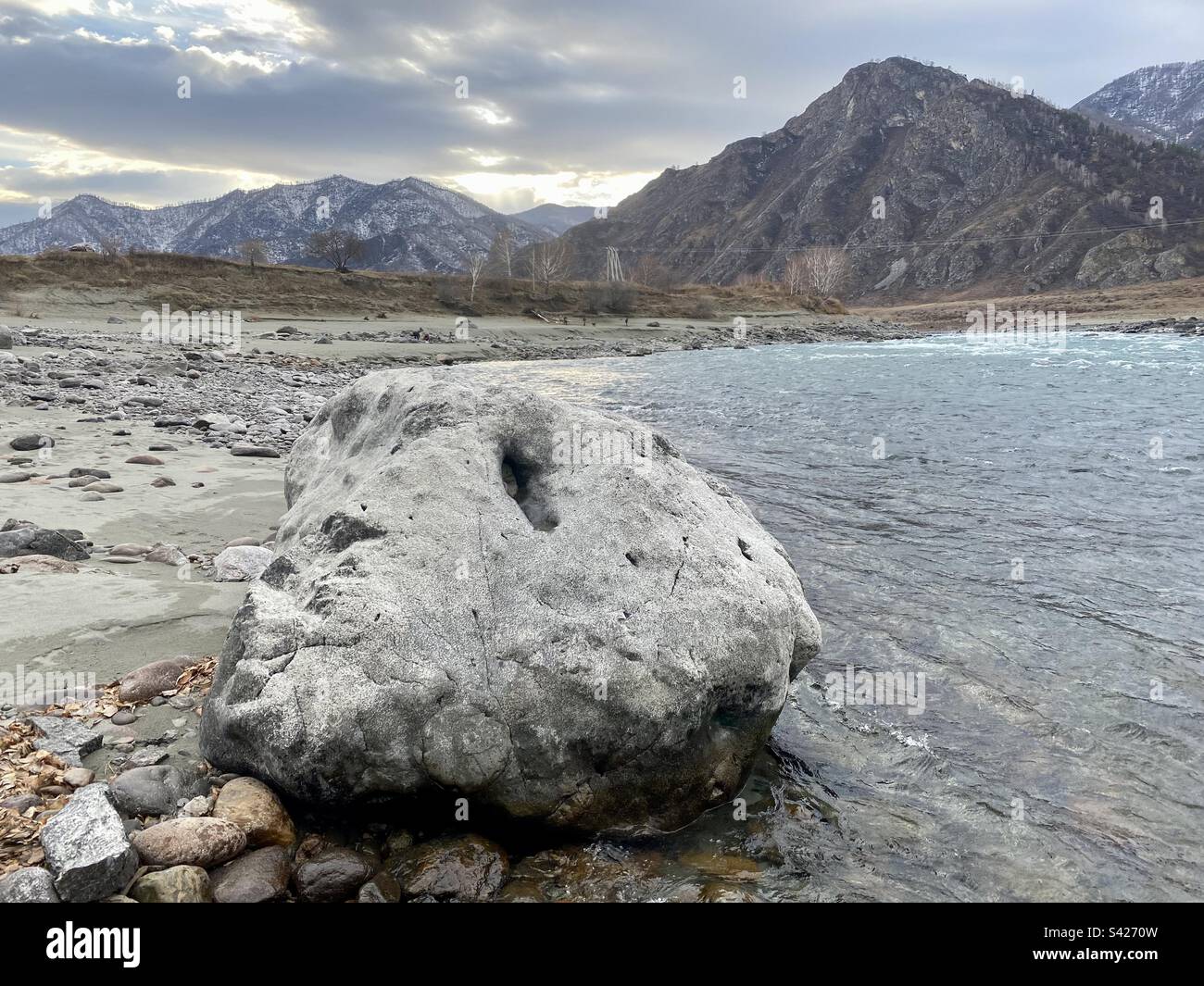 A large stone lies on the bank of the Katun River in the Altai Mountains at sunset in Siberia. - Smartphone Captured Stock Image