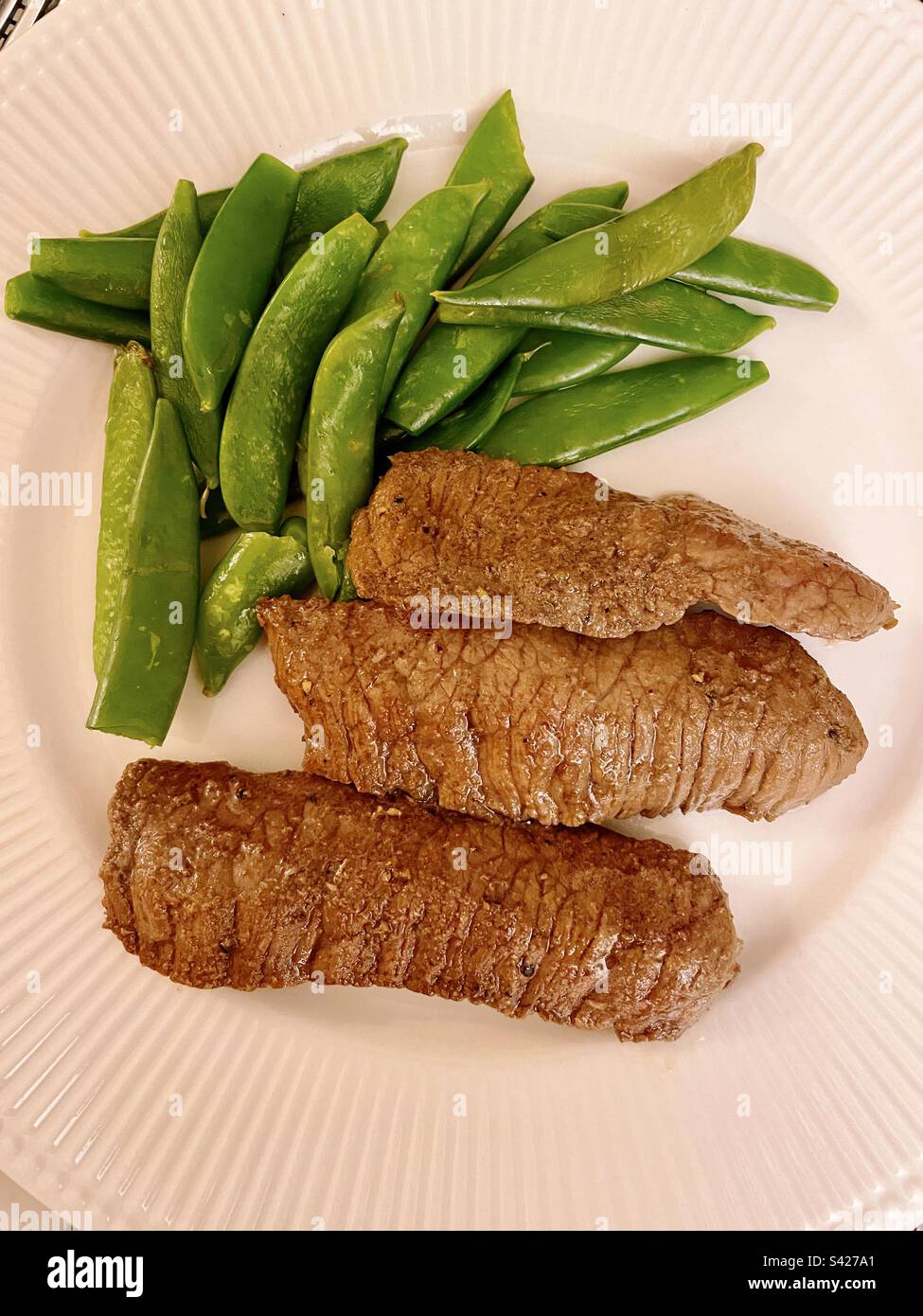 Flat lay of a gourmet meal of marinated flank steak and snap peas, 2023, USA Stock Photo Alamy