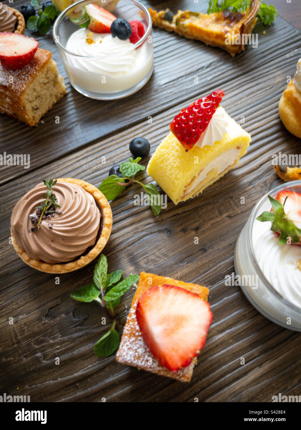 Small afternoon tea cakes on plain brown wood background - Smartphone Captured Stock Image