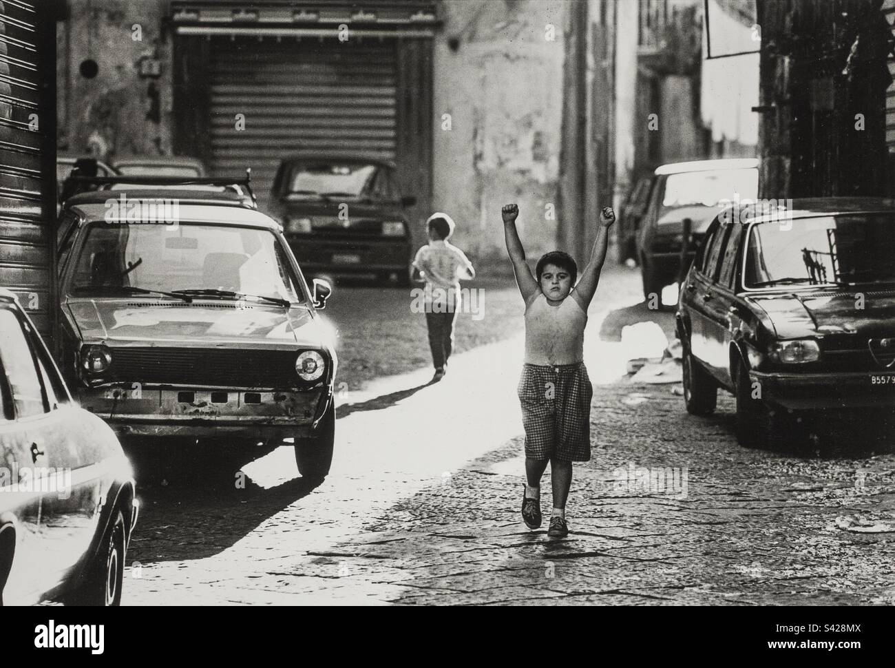 Naples street boy flexing his muscles in the back streets. - Smartphone Captured Stock Image