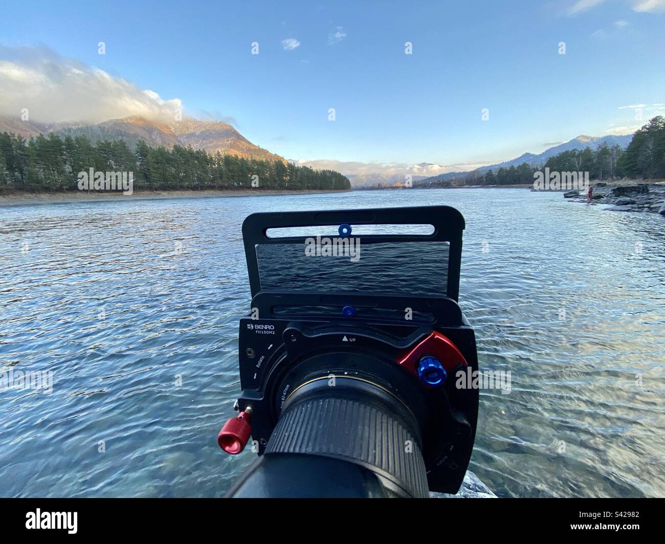 The square system of photographic light filters of the company Benro on the camera object on the river in the mountains. - Smartphone Captured Stock Image The square system of photographic light filters of the company Benro on the camera object on the river in the mountains. - Smartphone Captured Stock Image
