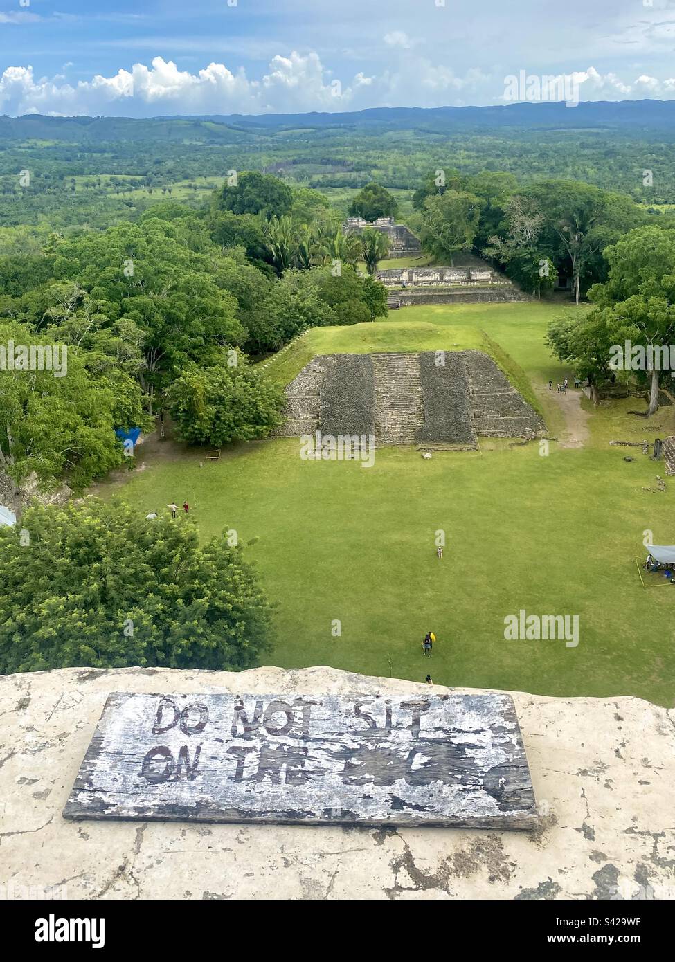 “Do Not Sit On The Edge” warning sign on top of the 130 foot high El Castillo ruin at Xunantunich Archaeological Reserve, Belize - Smartphone Captured Stock Image
