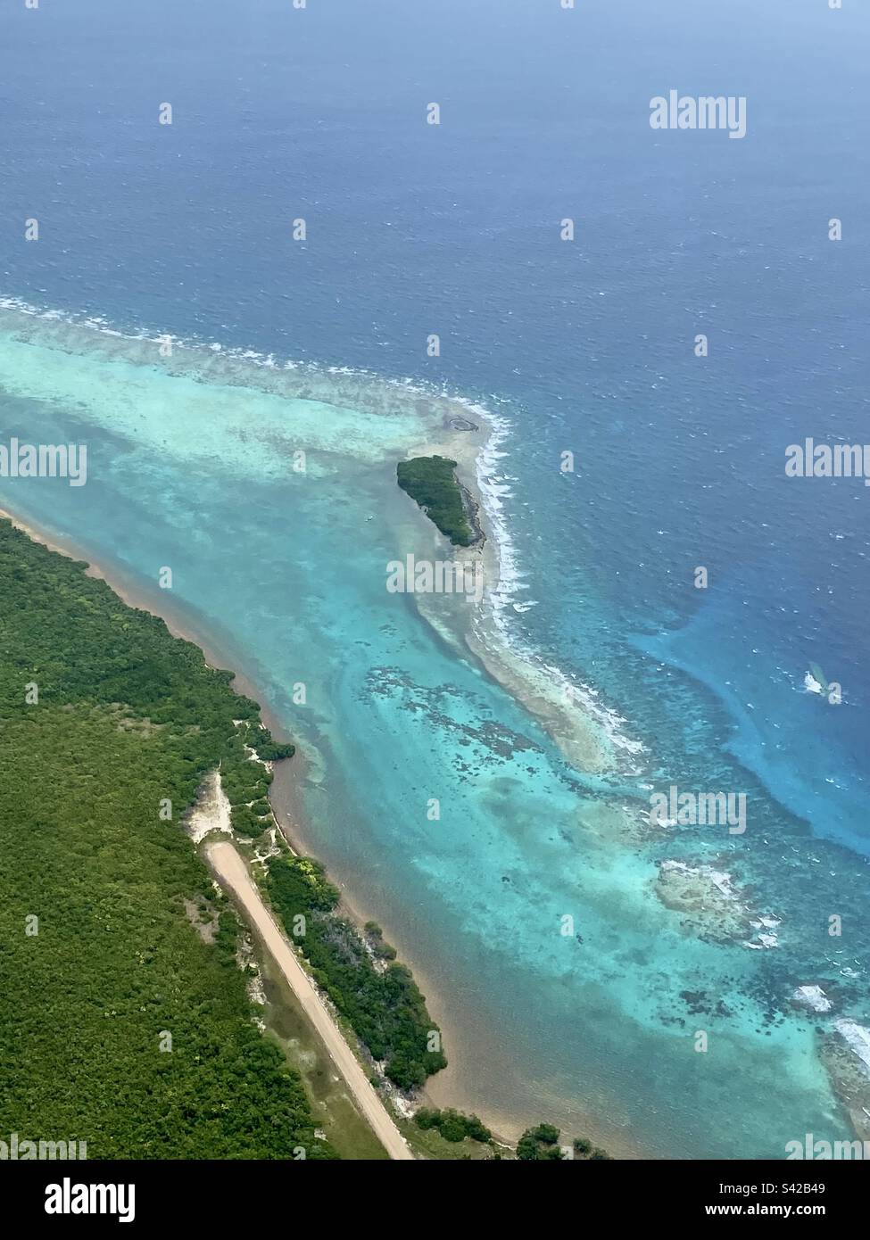 Aerial view of beautiful blue water and lush vegetation at Blackbird Caye, with airstrip near the waters edge, Turneffe Atoll, Belize - Smartphone Captured Stock Image