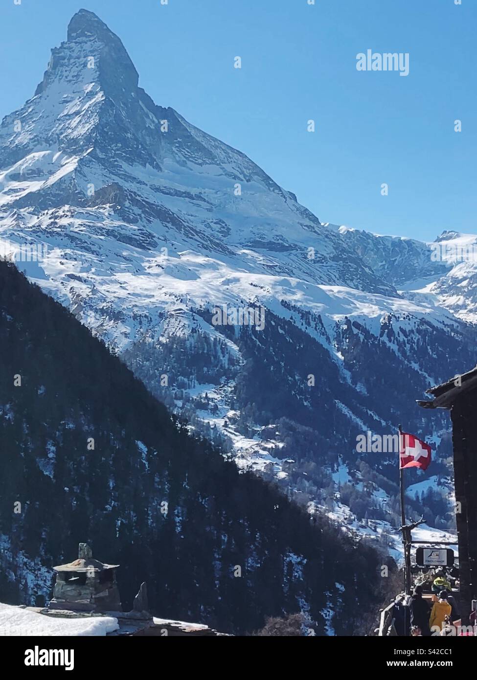 The Matterhorn seen from Sunnegga, Zermatt, with the Swiss flag flying in front. - Smartphone Captured Stock Image The Matterhorn seen from Sunnegga, Zermatt, with the Swiss flag flying in front. - Smartphone Captured Stock Image