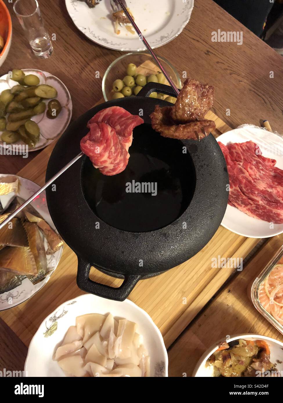 Cooking fondue with marbled beef, squid, fish and other snacks on the table - Smartphone Captured Stock Image