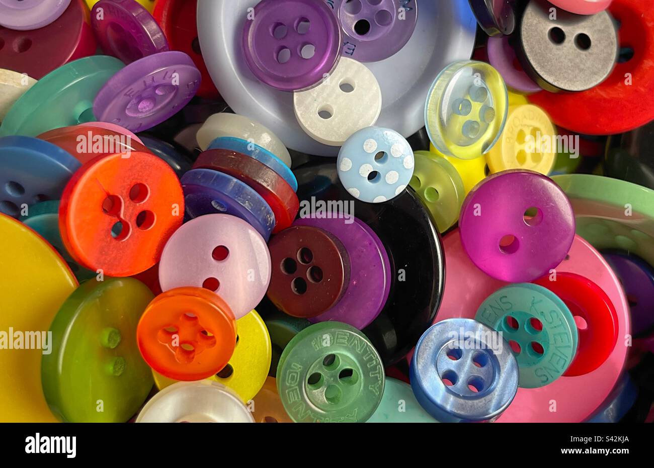 Multicoloured sew on buttons of all different shapes and sizes. Close up, piled up in a bundle. Stock Photo